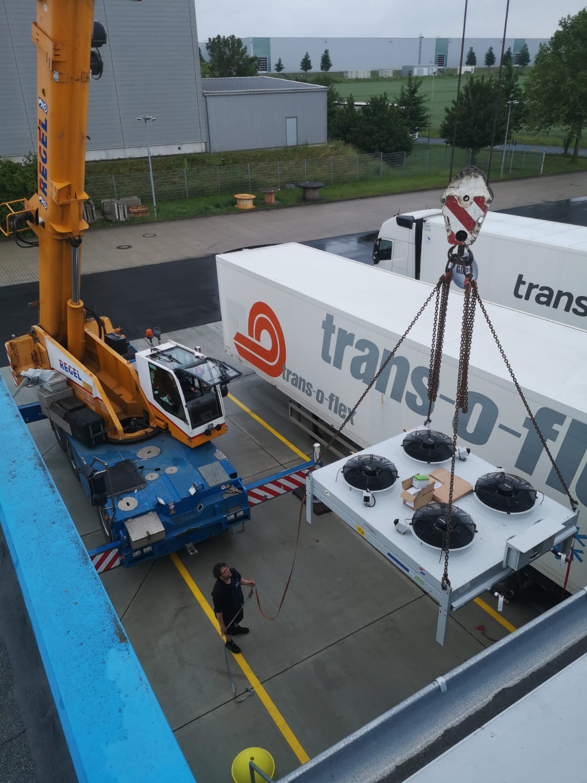 Kran hebt eine Kälteanlage mit vier Ventilatoren zur Montage an